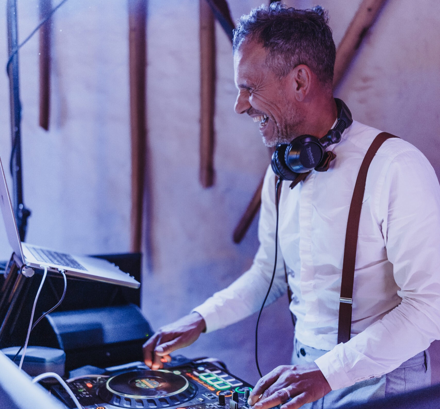 Hochzeits-DJ Ralf Esser lacht am DJ-Pult auf einer Hochzeitsfeier